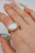 Load image into Gallery viewer, Photo is zoomed into a hand wearing a gold filled wire wrapped coin shaped freshwater pearl, handmade, ring on the pointer finger.
